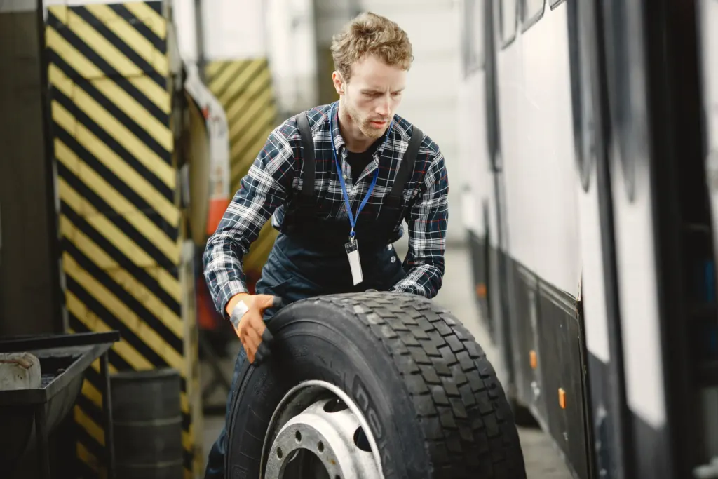 Mechanic handling a heavy truck tire in the service bay